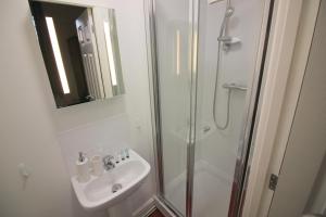 a white bathroom with a sink and a shower at Cambridge City Rooms by Paymán Club in Cambridge