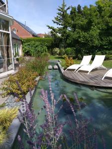 un jardín con 2 sillas y un barco en el agua en Le Mont Saint Roch , chambre d'hôtes, B&B, en Nivelles