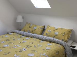 a bed with a yellow comforter and two pillows at Ty Glo Cottage in Brecon