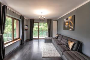 een woonkamer met een bank en een aantal ramen bij Tampa Gardens Apartments - Adults Only in Braşov