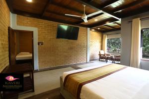 a bedroom with a bed and a tv on a brick wall at Kaveri Resort Sigiriya in Sigiriya