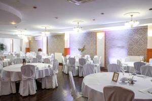 een feestzaal met witte tafels en stoelen bij First Hotel in Tczew