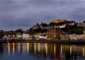 a city lit up at night with buildings and the water at Panoramic Harbour View Apartment in Oban