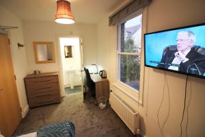 ein Wohnzimmer mit einem Flachbild-TV an der Wand in der Unterkunft Cambridge City Rooms by Paymán Club in Cambridge