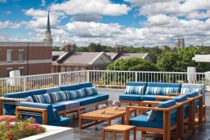 un patio con sillas azules y mesas en un balcón en The Lumen, en Dallas