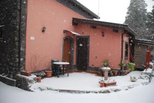 um edifício vermelho com neve no quintal em Etna Casa Llera-Antica casa siciliana em Milo