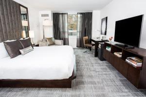 a hotel room with a bed and a flat screen tv at The Lumen in Dallas