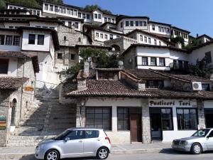 two cars parked in front of a building at Hostel Mangalem in Berat