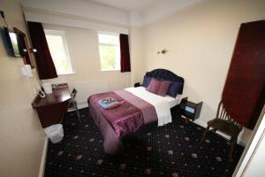 a hotel room with a bed and a desk at Avalon Guest House in Leeds