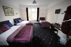 a hotel room with two beds and a tv at Avalon Guest House in Leeds