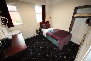 Habitación pequeña con cama y lavamanos en Avalon Guest House en Leeds