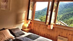 een slaapkamer met een bed en een groot raam bij Le Petit Chalet - Nice Wallis View in Ovronnaz