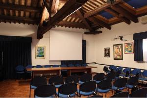 uma sala de conferências com cadeiras, uma mesa e um ecrã em Ristorante Alloggio Ostello Amolara em Adria
