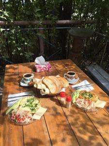a wooden table with two pizzas and cups of coffee at Guest House Dompolski in Gyumri