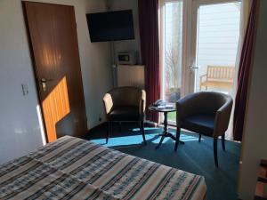 a hotel room with a bed and two chairs and a table at Hotel Zee en Duin in Katwijk
