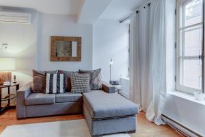 uma sala de estar com um sofá, uma cadeira e uma janela em Les Immeubles Charlevoix - Le 1173 em Quebeque