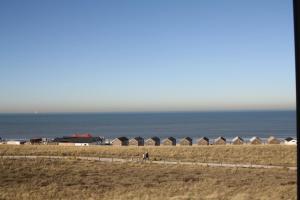 une plage avec une rangée de cabanes de plage dans l'établissement Hotel Zee en Duin, à Katwijk