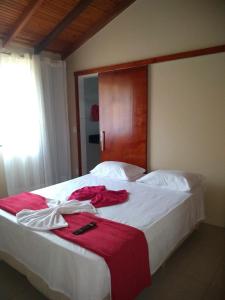a bedroom with a large white bed with red sheets at Pousada Bontempo in Pirenópolis