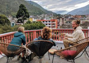 a group of people sitting in chairs on a balcony at Erupcion Art Hotel & Hostel in Baños