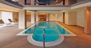 uma grande piscina num grande quarto com cadeiras em Hotel Zum Löwen - Al Leone em Meltina