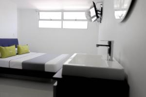 a bedroom with a bed and a sink and a window at 3H hotel centro histórico in Medellín