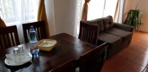a dining room table with a bottle of water and a couch at Hostal Casa Amarilla San Vicente de Tagua Tagua in San Vicente de Taguatagua