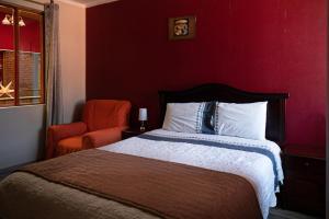 a red bedroom with a bed and a chair at Tonito Hotel in Uyuni