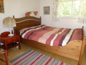 1 dormitorio con cama de madera, lámpara y mesa en Prästmyrens Vandrarhem en Ransäter