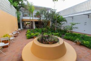 un edificio con un patio con plantas, mesas y sillas en La Gloria Hotel by BespokeColombia, en Mompox