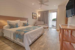 La Gloria Hotel by BespokeColombia في مومبوس: غرفة نوم بسرير وكرسي وتلفزيون
