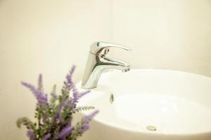 La salle de bains est pourvue d'un lavabo avec robinet et de fleurs violettes. dans l'établissement La Familia, à San Blas