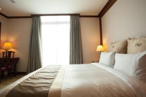 a bedroom with a large white bed with a window at Rich Garden Hotel in Taipei