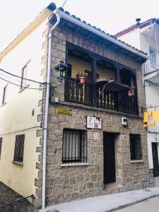 un edificio de piedra con un balcón con flores. en Casa SPA El Rincón del Duende, en Pedro Bernardo