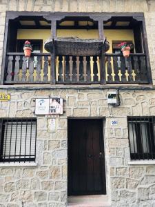 un edificio de piedra con un banco en el balcón en Casa SPA El Rincón del Duende, en Pedro Bernardo