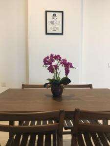 una mesa de madera con un jarrón con flores púrpuras. en PM Octagon Ipoh Suites & Apartment 1, en Ipoh