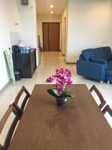 un tavolo di legno con un vaso di fiori sopra di PM Octagon Ipoh Suites & Apartment 1 a Ipoh