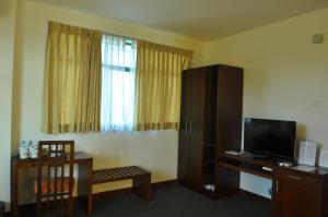 una habitación de hotel con TV y silla y una habitación en Amaara Sky Hotel Kandy, en Kandy