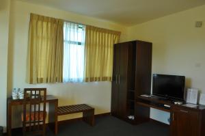 a hotel room with a tv and a chair and a room at Amaara Sky Hotel Kandy in Kandy