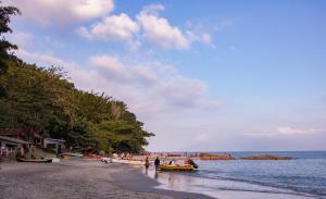 a beach with a group of people and boats on it at Apartamentos de Férias por Temporada Martim De Sá in Caraguatatuba