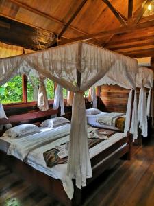 a bedroom with three beds with a canopy at Borneo Natural Sukau Bilit Resort in Bilit