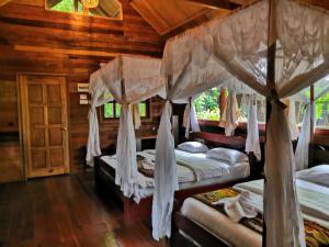 a bedroom with four beds in a wooden cabin at Borneo Natural Sukau Bilit Resort in Bilit