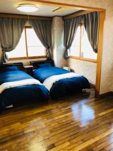 two beds in a room with two windows at Apartment at Toemu Nozawa in Nozawa Onsen