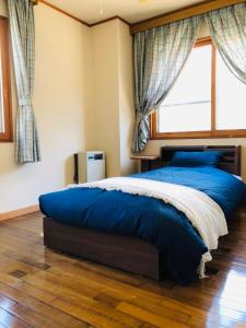 Un dormitorio con una gran cama azul y una ventana en Apartment at Toemu Nozawa, en Nozawa Onsen