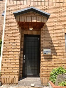 un edificio de ladrillo con una puerta negra con una ventana en Apartment at Toemu Nozawa, en Nozawa Onsen