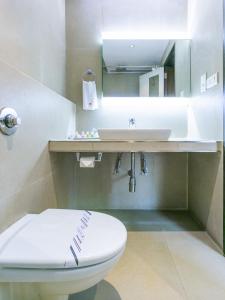 a bathroom with a white toilet and a sink at The Roa Hotel in Mumbai