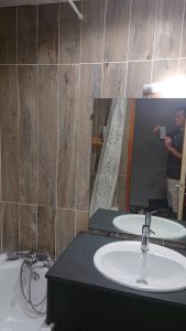 Ein Mann fotografiert ein Badezimmer mit Waschbecken. in der Unterkunft Les Olympiades in Bourg-Saint-Maurice