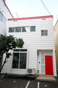 Biały dom z czerwonymi drzwiami w obiekcie kODATEL コダテル 札幌大通公園 アネックス w mieście Sapporo
