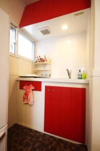 a kitchen with red cabinets and a sink at kODATEL コダテル 札幌大通公園 アネックス in Sapporo