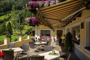 un patio al aire libre con mesas, sillas y flores en Hotel Jägerhof en Kaunertal