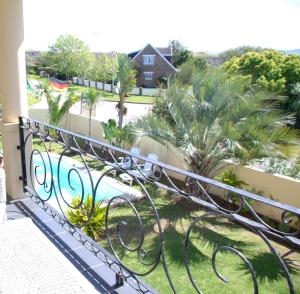 a balcony with a view of a pool and palm trees at Mandalay Guest House Plettenberg Bay in Plettenberg Bay